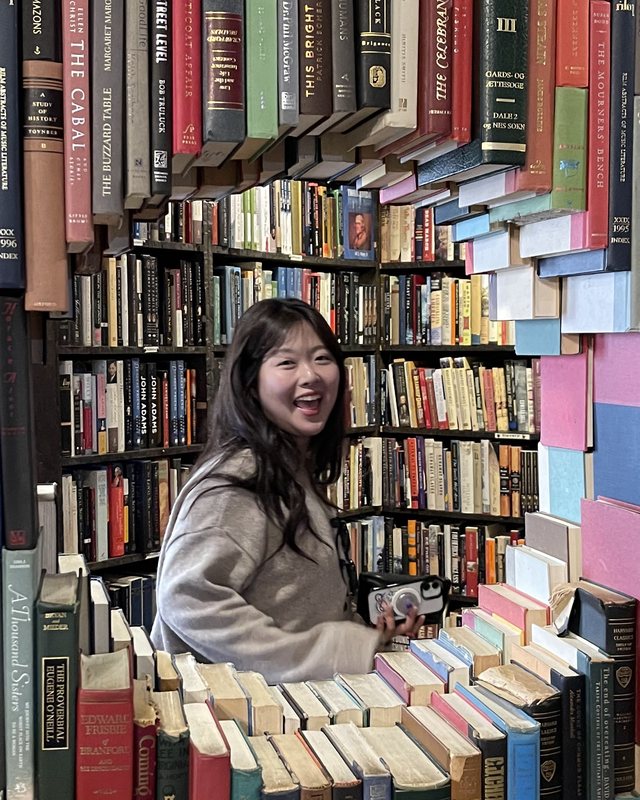 Kyeongseon Kim smiling between bookshelves
